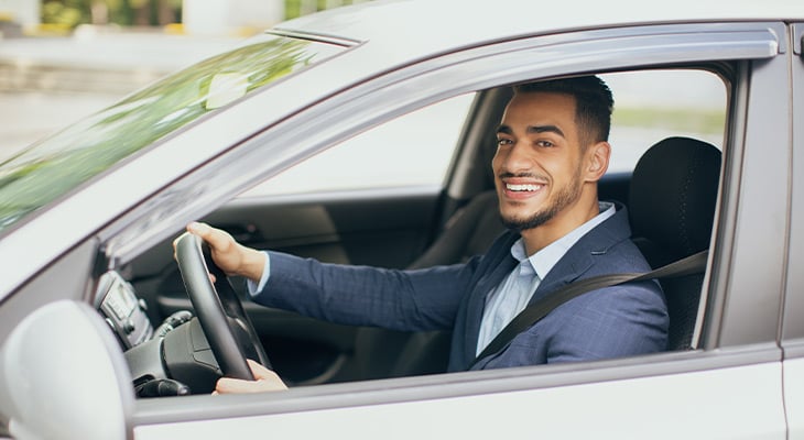 Man is smiling as he holds the steering wheel