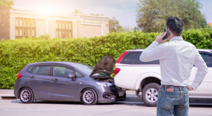 Man talking on the phone while looking at 2 cars that crashed into each other