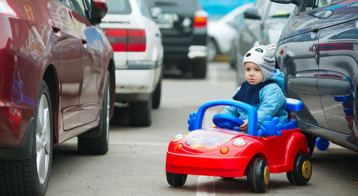 Parking lot accident: sad, little boy in his toy car