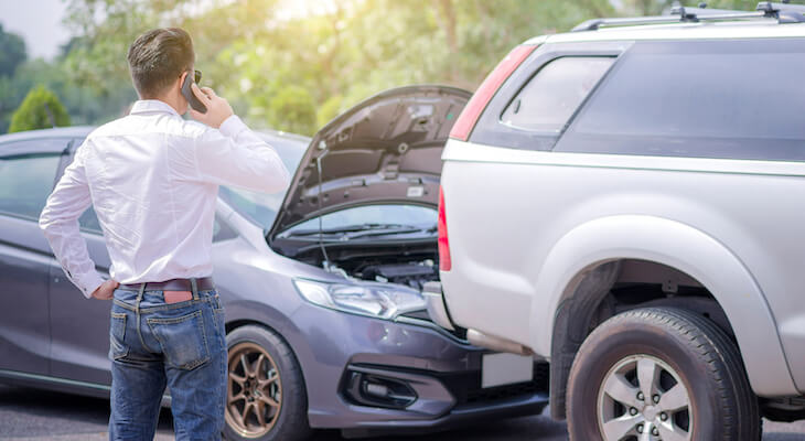 What is umbrella insurance: man talking on the phone while looking at cars that crashed into each other