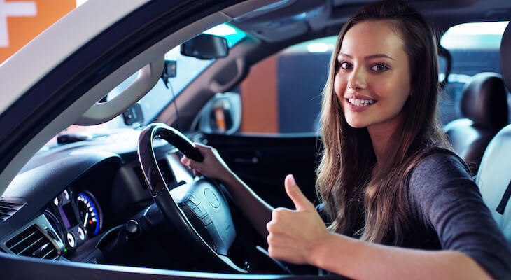 Woman behind the steering wheel, giving the thumbs-up