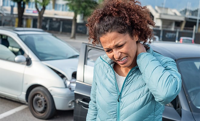 woman rubbing neck after car crash