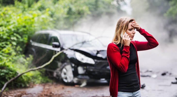 Worried woman talking on the phone after a car accident