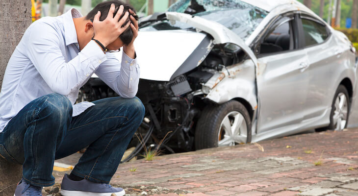 Does a car need to be insured: stressed man beside a wrecked car