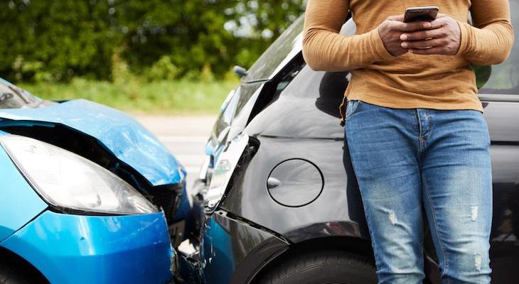 Person texting while standing beside a car accident
