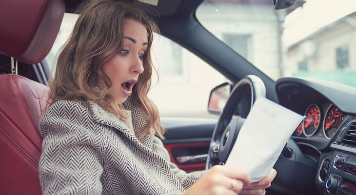 Shocked woman reading documents in her car