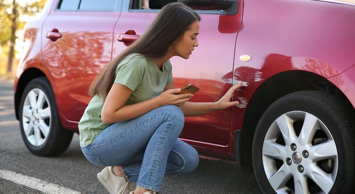 Woman checking a scratch on her car
