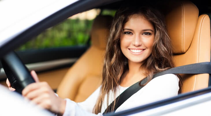 Woman smiling at the camera while sitting inside her car