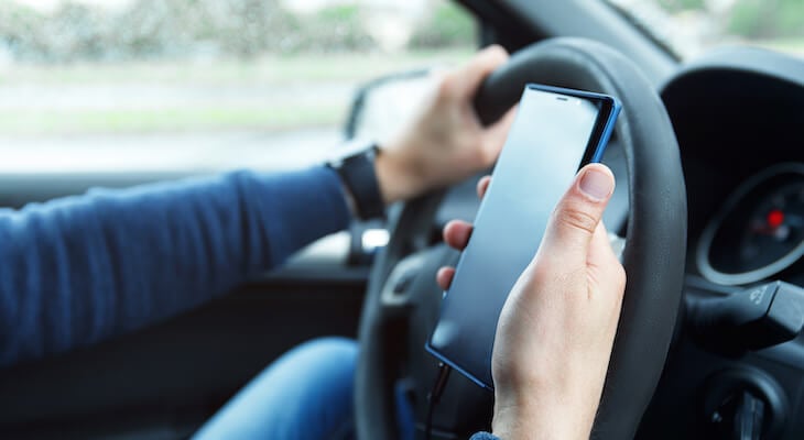 Person holding a phone while driving a car