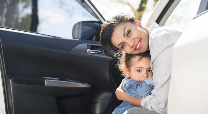 mother leaning out of car hugging her daughter