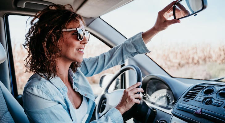 When to buy car insurance: woman adjust her car's rearview mirror