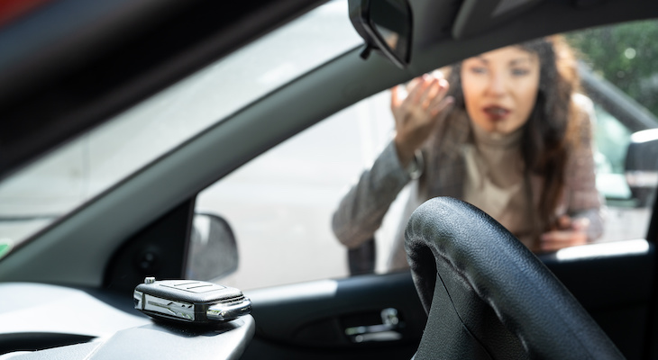 Woman looking at the keys she left inside her car