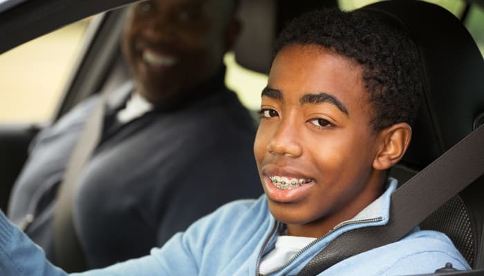Young driver with dad smiling after getting cheap car insurance for young drivers