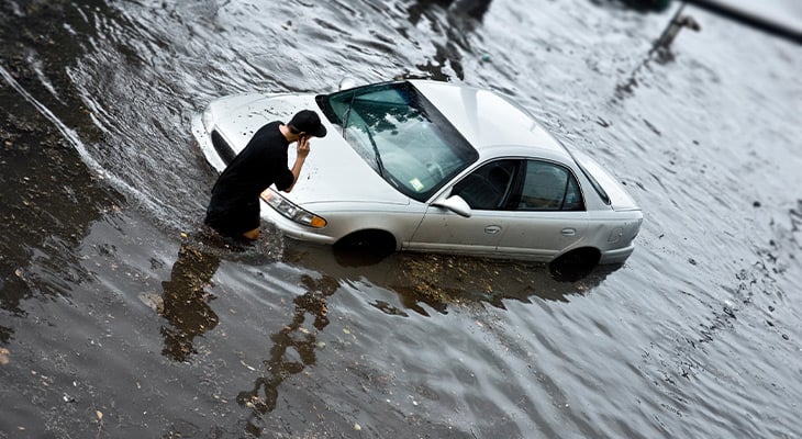 man by his car in a flooded area
