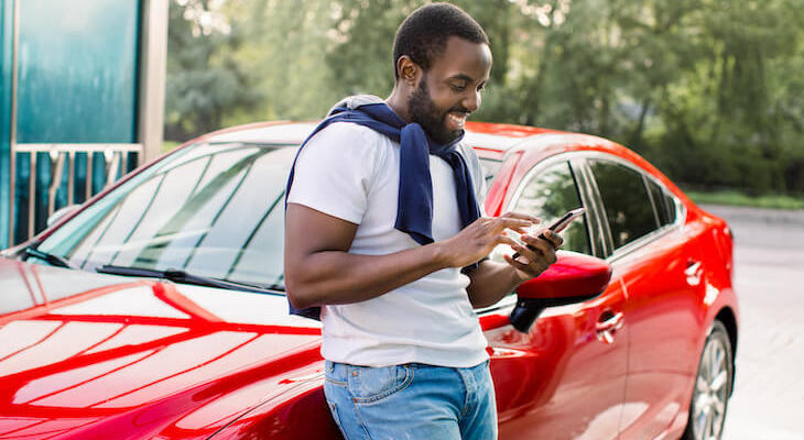 What color cars are more expensive to insure: man happily using his phone while standing beside his car