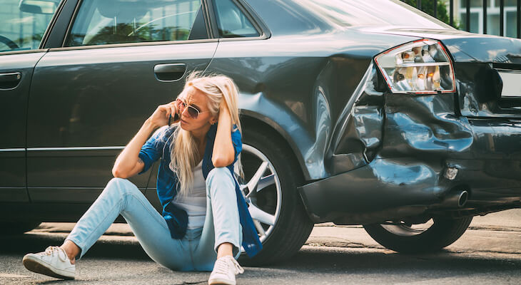 New car replacement insurance: stressed woman talking on the phone after a car accident