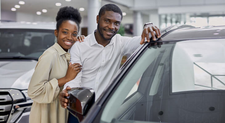 Couple happily standing near a car
