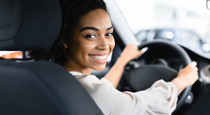 Very cheap car insurance no deposit: young woman smiling while driving a car