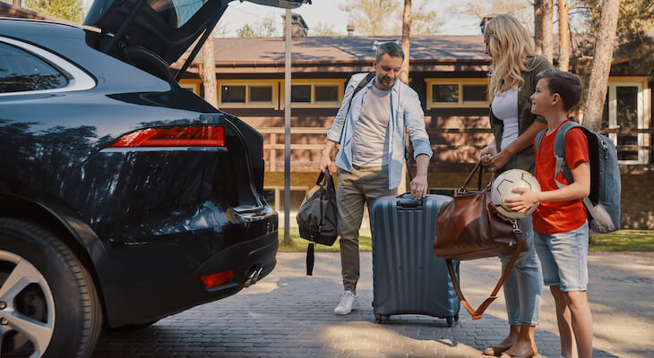 Which gender pays more for car insurance: family loading their luggage into the trunk of their car