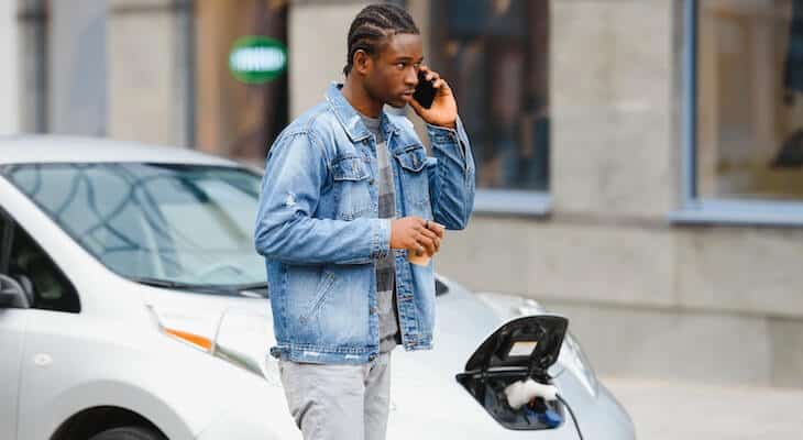 Man on his phone while charging his car