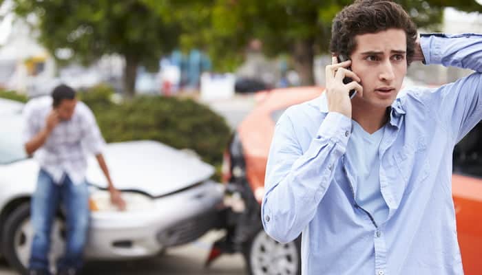 Man from car crash on phone wondering how much auto insurance goes up after an accident