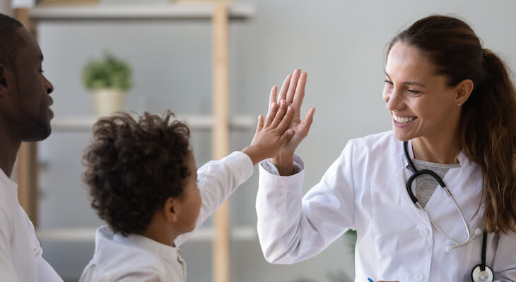 Doctor high-fives child, who is being held by father