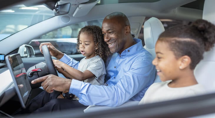 Buying a electric car: happy family inside an electric car
