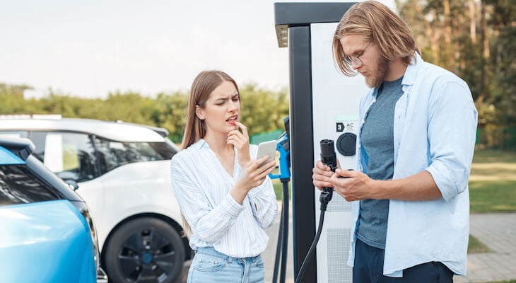 Buying a electric car: two people figuring out how to use a car charger
