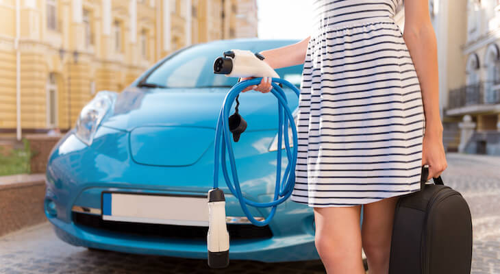 Buying a electric car: woman carrying a car charger