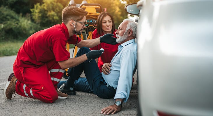 How much does an ER visit cost; EMTs helping an old man