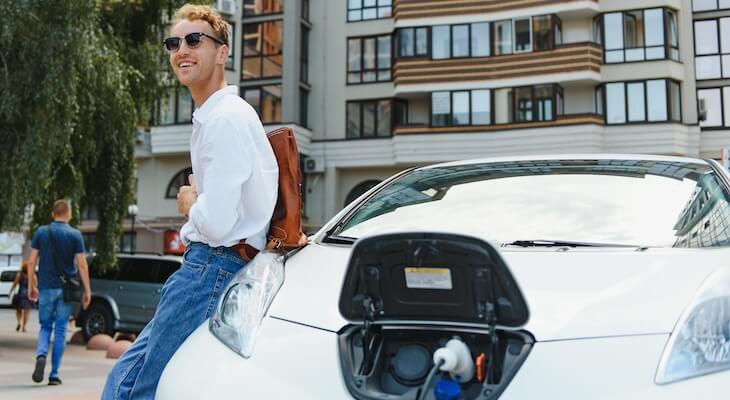 Electric car with longest range: man happily charging his car