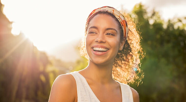 Beautiful woman stands in sun and smiles