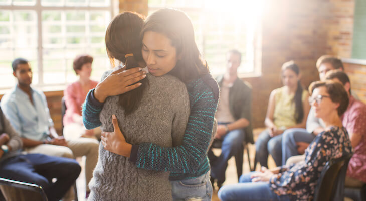 Two people hug in the center of group therapy circle