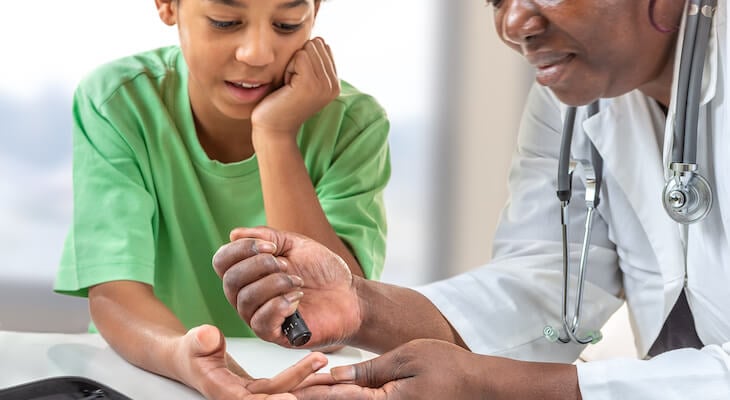 Doctor testing a boy's blood sugar level