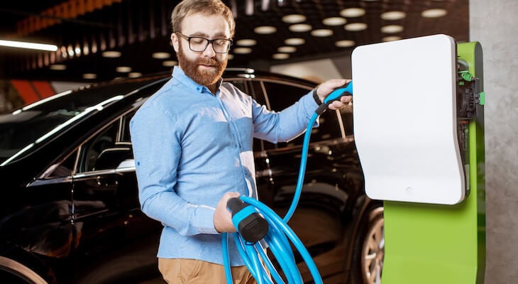 Best EV charging station: happy man holding an EV charger