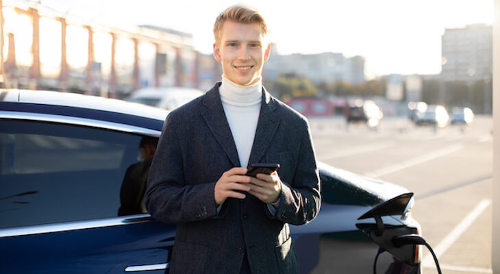 Tesla CPO: man holding his phone while charging his EV