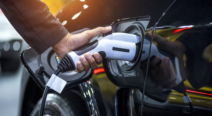Close-up of a person's hand charging an electric car