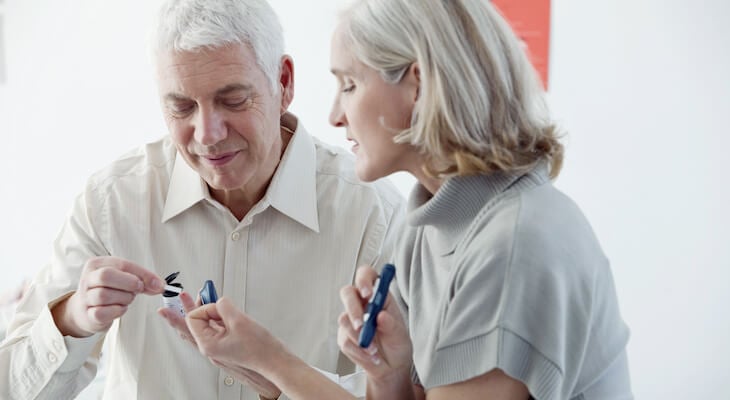 Cost of diabetes: elderly couple testing their blood sugar