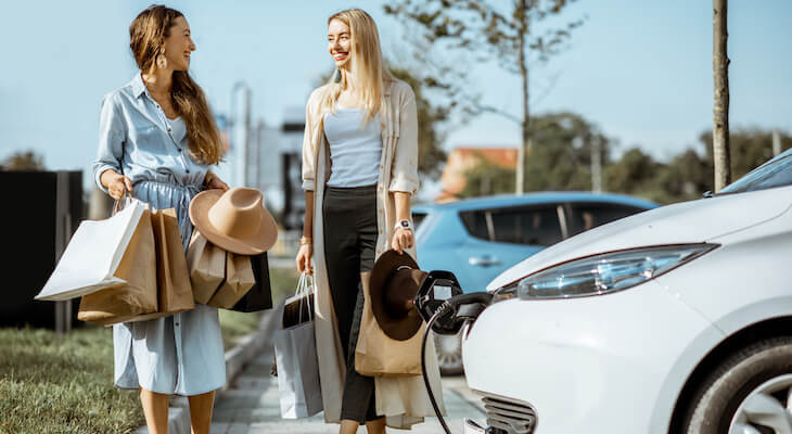 Women talking in front of a charging car