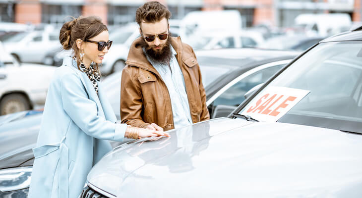 Salvage title: couple checking a car on sale