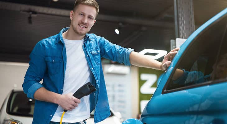 Fastest EV charger: man standing beside his car while holding an EV charger