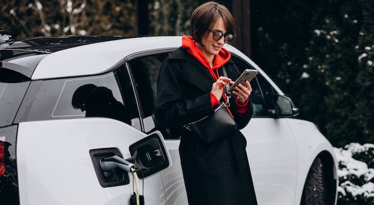 Woman using her phone while waiting for her car to finish charging