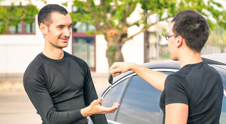 Are older cars cheaper to insure: person handing a key to another person