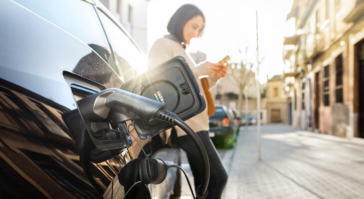Free EV charging stations: woman waiting for her car to finish charging