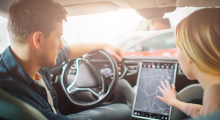 Why is Tesla insurance so high: couple looking at an electric dashboard