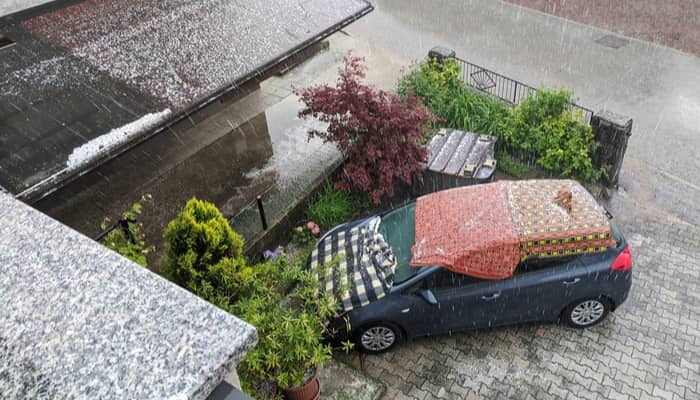 car in a hail storm covered by blankets to prevent damage