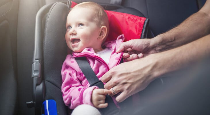 Happy baby in a child safety seat