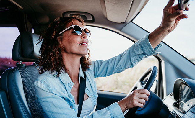 Woman with sunglasses checking her rear view mirror