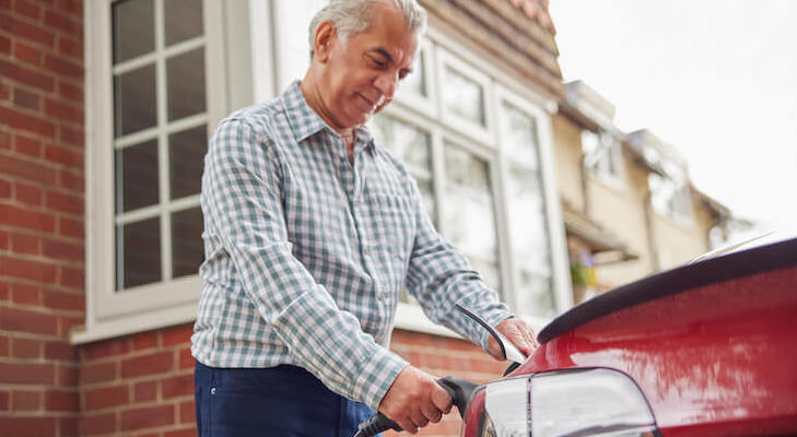Elderly man charging his electric car