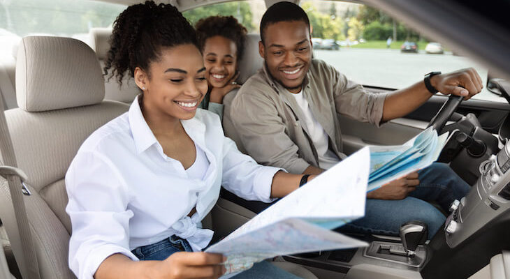 Cheap car insurance South Carolina: family happily looking at a map while in their car